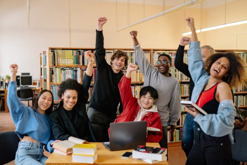 Jovens celebrando em biblioteca, simbolizando resultados do Enem 2023
